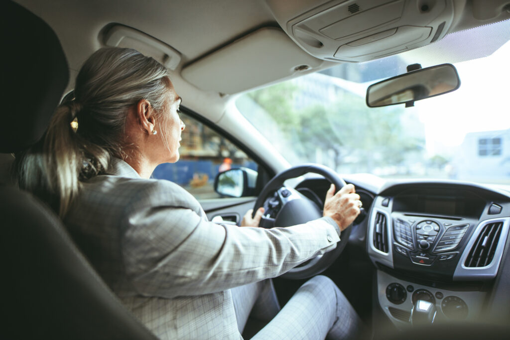 Businesswoman driving a car. Shot from behind of senior female in businesswear driving a car.