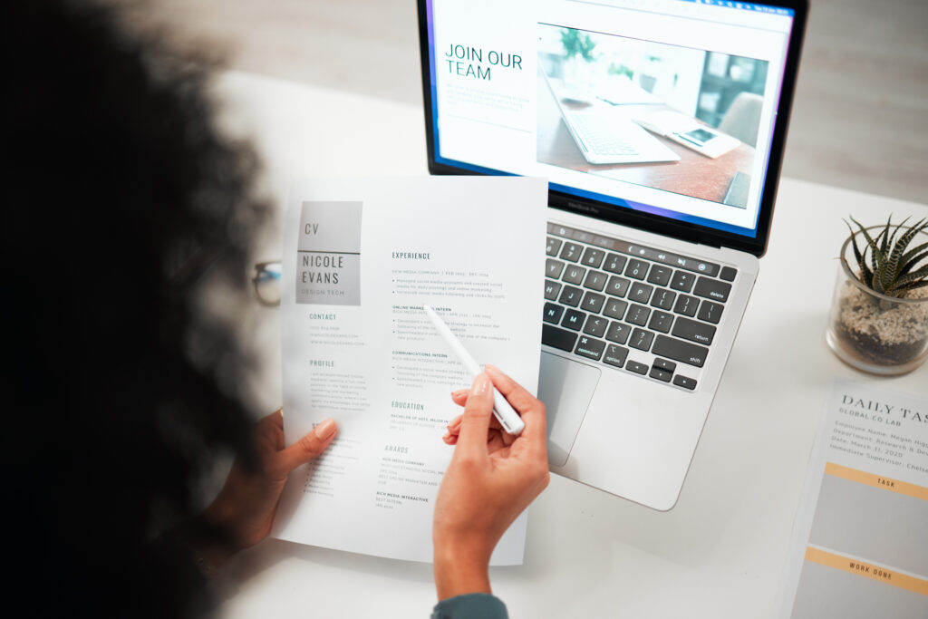 Hands, pen and human resources with CV, laptop with hiring news on company website and recruitment in office. Person reading resume, employee choice and onboarding, job application and back view.